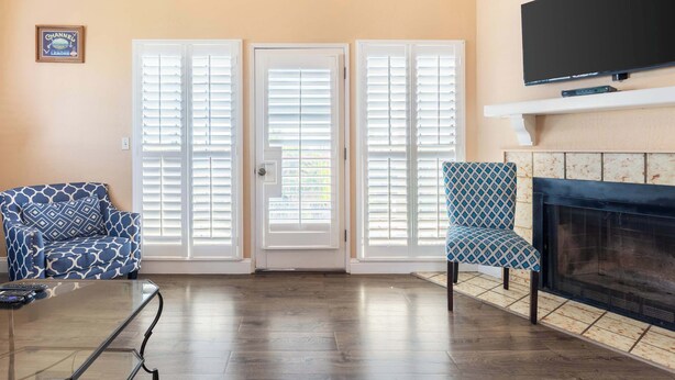 A living room with a sofa, a patterned armchair, a fireplace, and a television mounted above it. - Santa Cruz Retreat Near Beach with Free Parking (Santa Cruz)