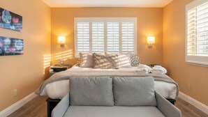 A bedroom with a bed, two bedside tables, a nightstand, a window with blinds, and wall-mounted lamps. - Santa Cruz Retreat Near Beach with Free Parking (Santa Cruz)