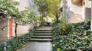 A narrow alleyway with steps leading to a building entrance, surrounded by greenery and a red door. - Santa Cruz Retreat Near Beach with Free Parking (Santa Cruz)