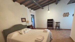 A bedroom with a bed, a nightstand, a chair, and a wooden bench. - Apartment located within an Agriturismo with swimming pool in Maremma n.2 (Scansano)