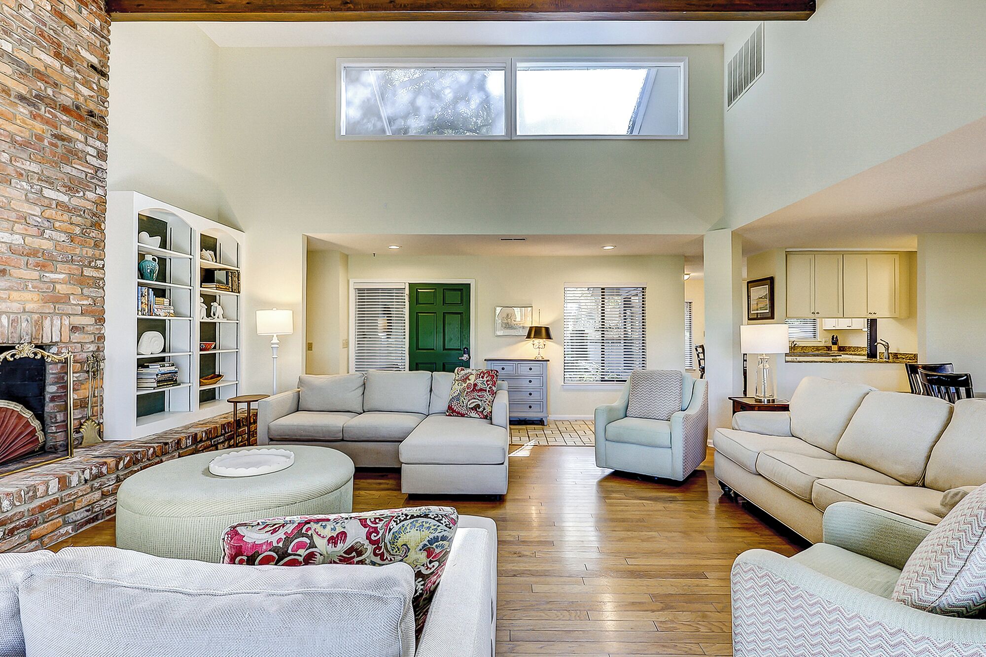 A spacious living area with a fireplace, multiple seating options, and a kitchen in the background.