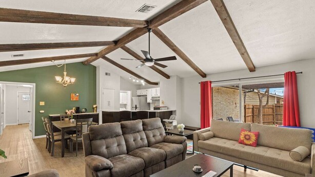 A spacious living area with a high ceiling, exposed wooden beams, a dining area, and a kitchen. - Incredible Location | King Bed | Sleeps 14 (San Antonio)