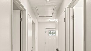 A narrow hallway with white doors and a wooden floor. - Incredible Location | King Bed | Sleeps 14 (San Antonio)