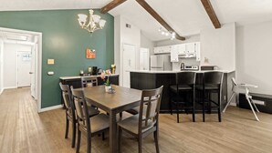 A dining area with a wooden table and chairs, a chandelier, and a kitchen in the background. - Incredible Location | King Bed | Sleeps 14 (San Antonio)