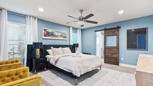A bedroom with a bed, a ceiling fan, a painting, and a door. - The Stafford Cottage-Close to The Pearl & Downtown (San Antonio)