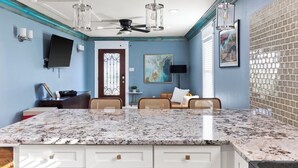 A kitchen with a granite countertop, white cabinetry, a ceiling fan, and a brick backsplash. - The Stafford Cottage-Close to The Pearl & Downtown (San Antonio)