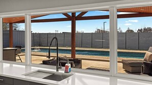A kitchen with a view of a backyard swimming pool, outdoor furniture, and a pergola. - Great Location-Huge Pool | Sleeps 14 | 2 King Beds (San Antonio)