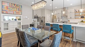 Une cuisine moderne avec des meubles blancs, un îlot central et des chaises bleues.