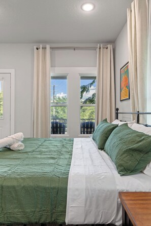 Ein Schlafzimmer mit Bett, Fenster und Blick ins Freie.