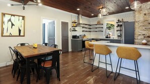 Une cuisine moderne dotée d’un îlot central, de planchers en bois et de luminaires suspendus.