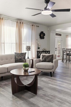 Un salon comprenant un canapé, un fauteuil, une table basse et un ventilateur de plafond.