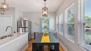 A kitchen with a dining table, a refrigerator, a sink, and a window with blinds.