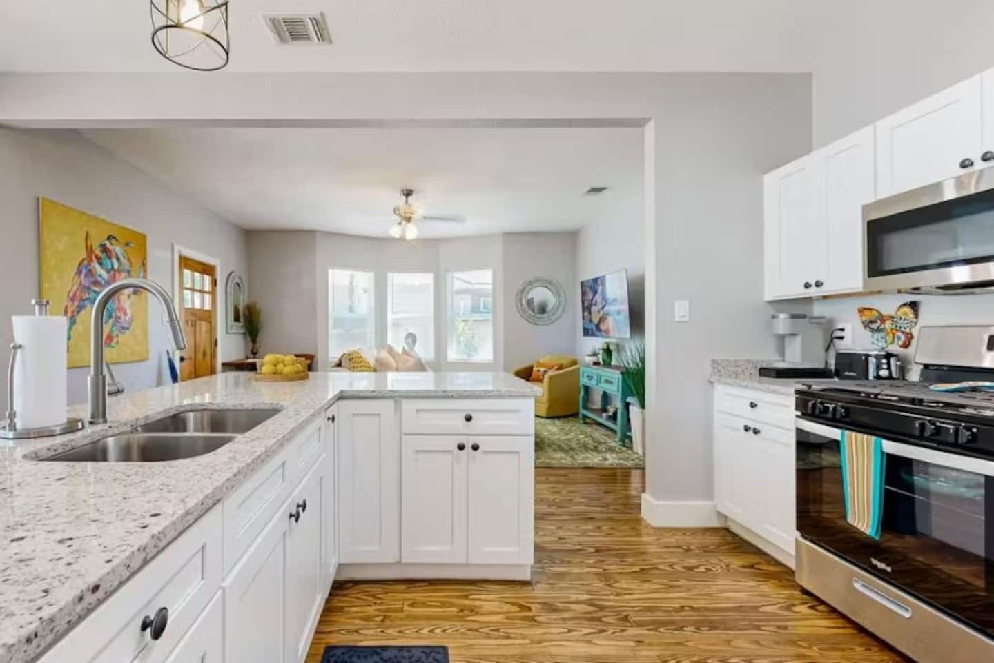 A modern kitchen with white cabinetry, a granite countertop, a built-in oven, and a microwave.