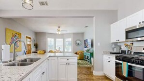 A modern kitchen with white cabinetry, a granite countertop, a built-in oven, and a microwave.