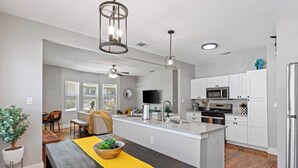 A modern kitchen with white cabinetry, a central island, and a dining area with a wooden table and yellow runner.