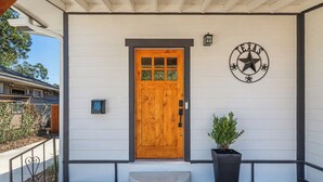 A house with a wooden front door, a mailbox, a potted plant, and a Texas state emblem on the wall.