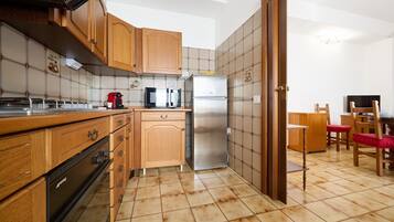 A compact kitchen with wooden cabinets, a stainless steel refrigerator, a microwave, and a coffee maker.
