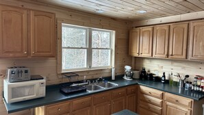 Een keuken met houten kastjes, een magnetron, een broodrooster, een spoelbak en diverse keukenapparaten.