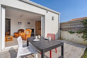 Eine offene Terrasse mit Tisch für zwei Personen, einer Couch und einem Sessel.