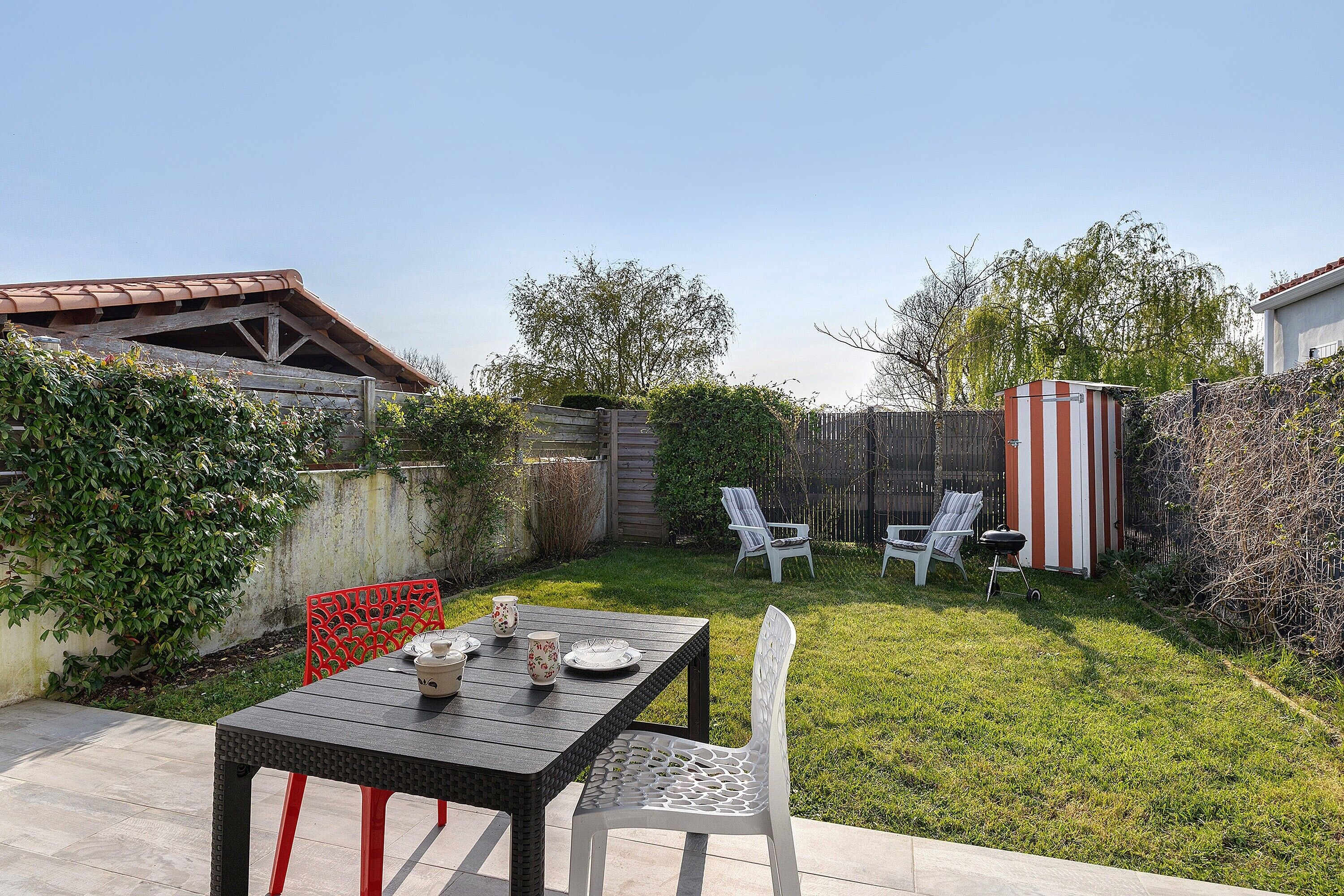 A patio with a table and chairs, a small shed, and a grassy yard.