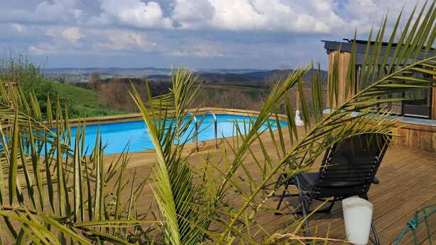A wooden deck with a swimming pool, a chair, and a white statue.