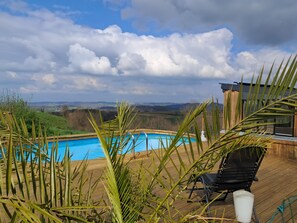 A wooden deck with a swimming pool, a chair, and a white statue. - Le gite loustaou d'élisa swimming pool jacuzzi billiards babyfoot party evjf evjg wedding (Lestelle-Bétharram)