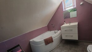 A bathroom with a bathtub, a vanity with a mirror, and a towel rack with towels.