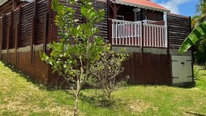 A red wooden building with a balcony, surrounded by grass and a few small trees. - Freddo's 2-4 persons with private pool (Capesterre-de-Marie-Galante)