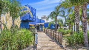 Un muelle de madera que conduce a un edificio con fachada azul y un letrero que dice "The Gulf".