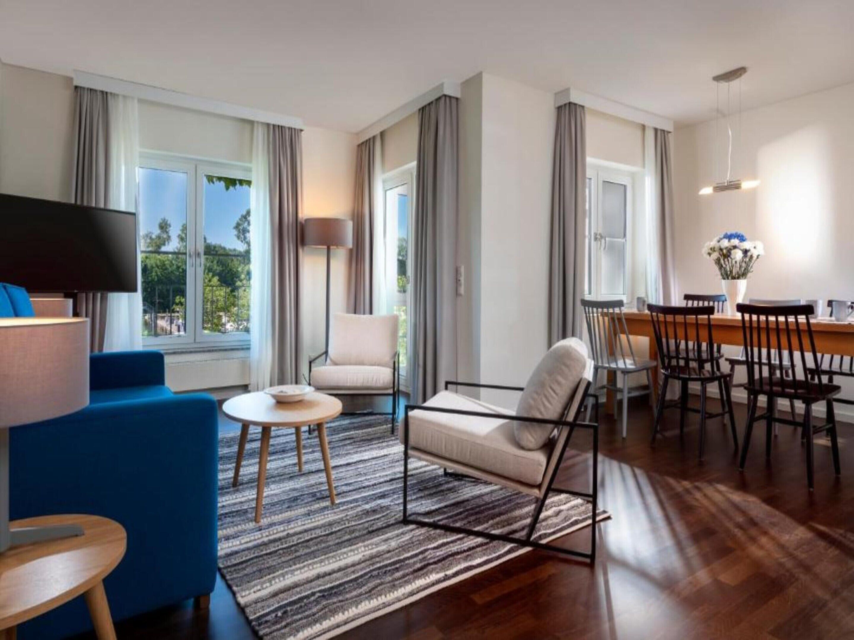 Una sala de estar moderna con sofá, sillón, mesa de comedor y sillas.