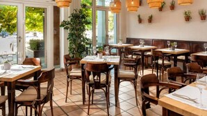 A restaurant interior with wooden tables and chairs, large windows, and hanging wicker lamps. - Sunday Resort Marina 3-bedroom Apartment (Rheinsberg)