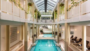 An indoor swimming pool with a glass ceiling, surrounded by columns and lounge chairs. - Sunday Resort Marina 3-bedroom Apartment (Rheinsberg)