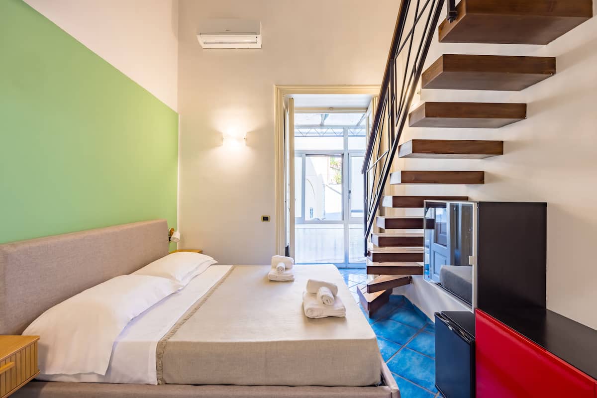 A hotel room with a bed, a TV, and a staircase.