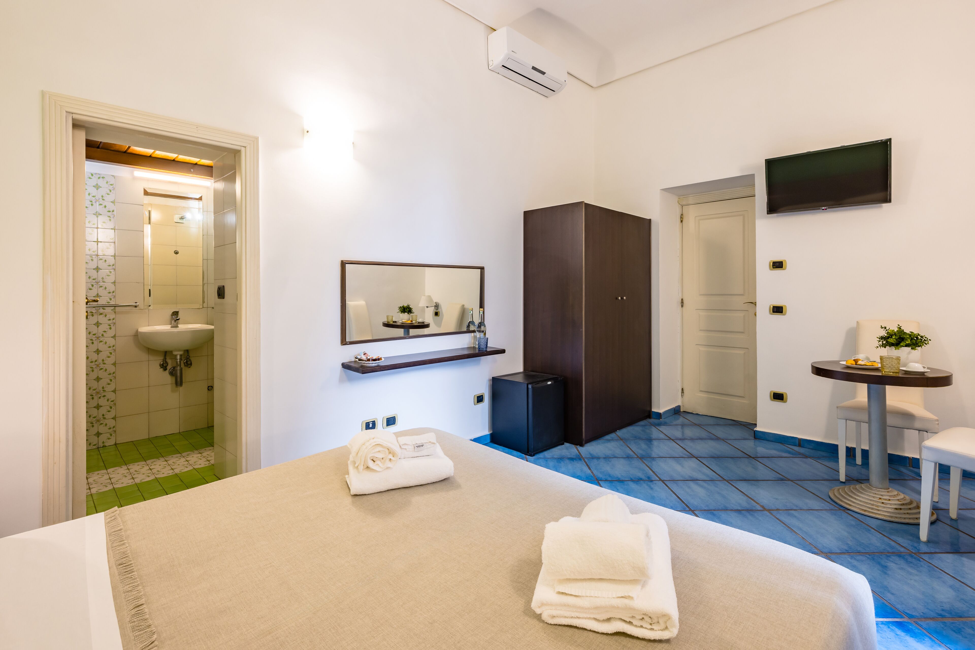 Ein Hotelzimmer mit Bett, Badezimmer, Fernseher und einem kleinen Tisch mit Pflanze.