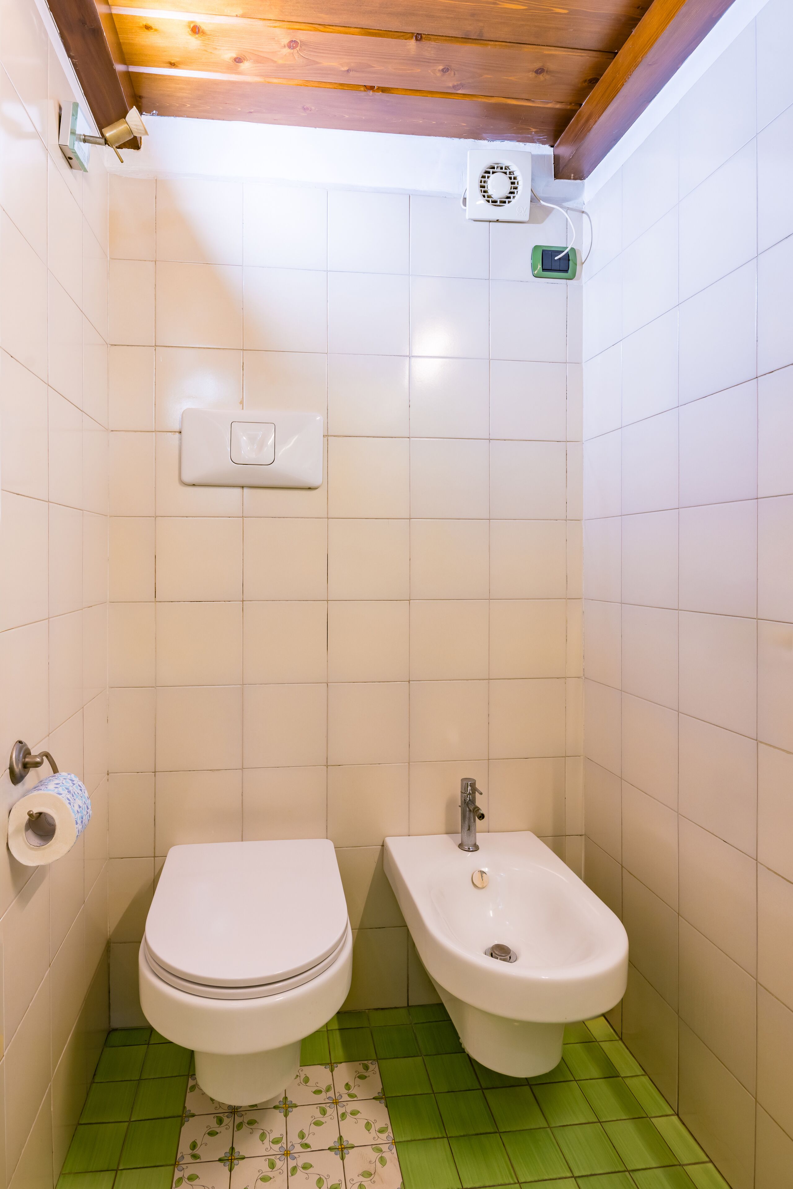 A small bathroom with a toilet, bidet, and a wall-mounted heater.