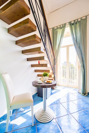 A modern interior with a wooden staircase, a round table with a plant, and a chair.