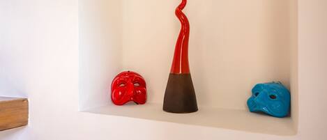 Three ceramic masks on a white shelf against a wall.
