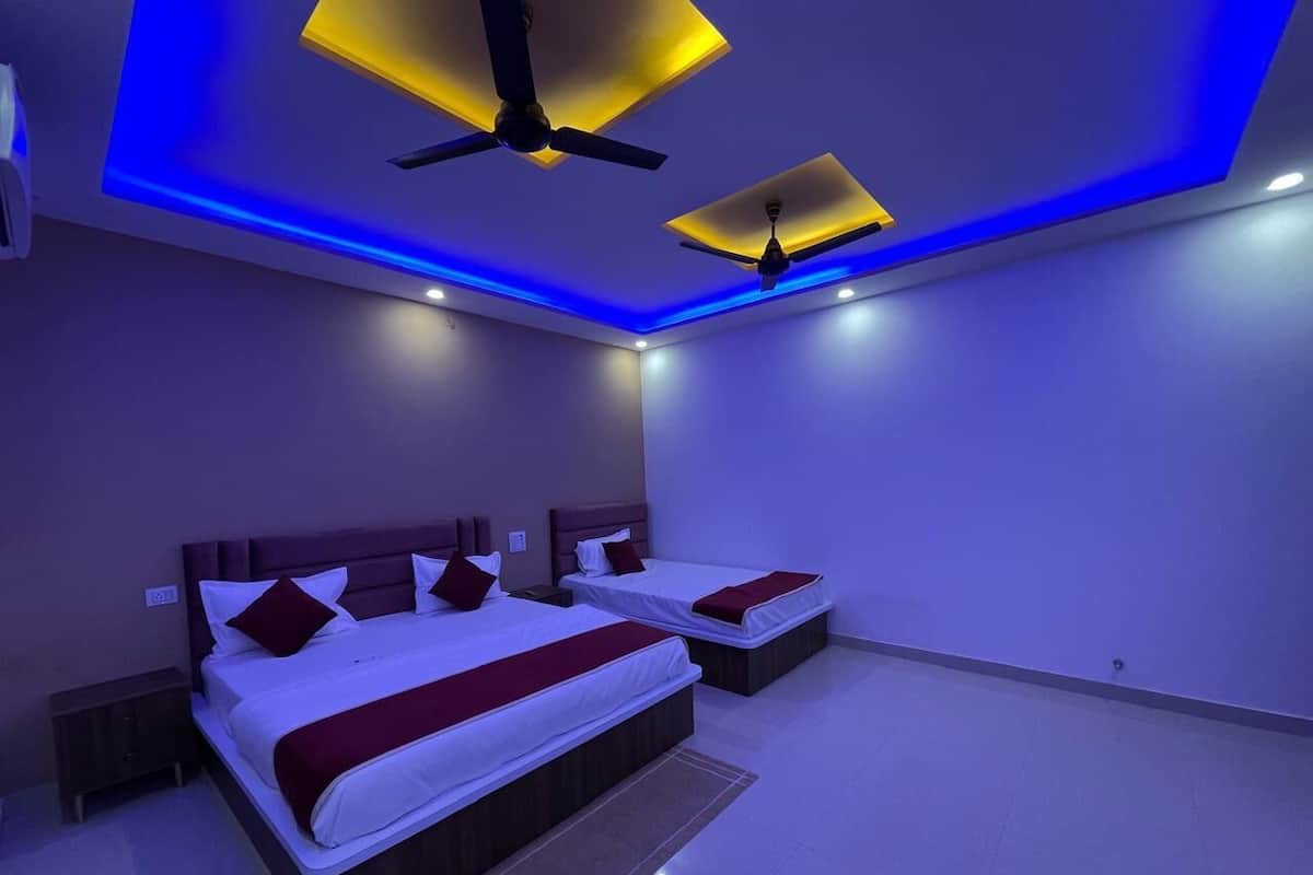 A modern bedroom with two beds, a ceiling fan, recessed lighting, and a dark wooden floor.