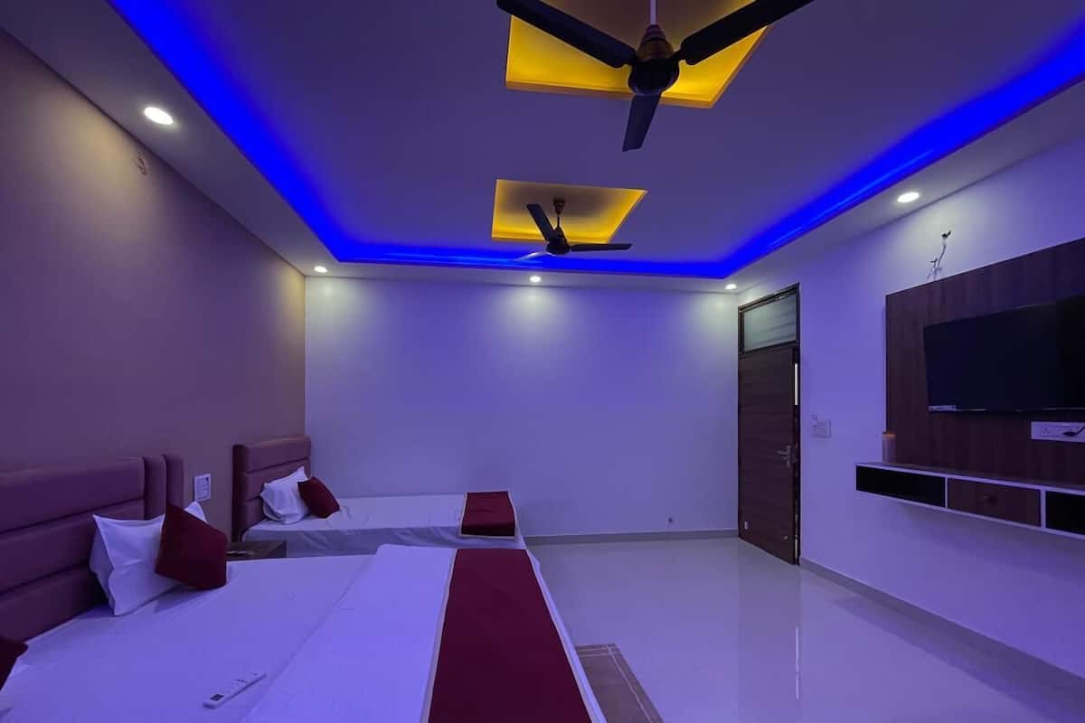 A modern hotel room with a large bed, two bedside tables, a flat-screen TV mounted on the wall, and a ceiling fan.