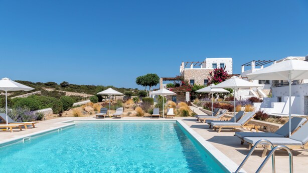 A clear blue pool with lounge chairs and umbrellas, surrounded by stone buildings and greenery. - Sand Key Villa 1 - A beautiful cycladic residence with 7 Bedrooms (Paros)