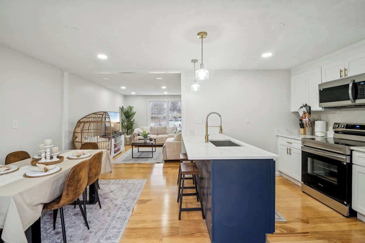 A modern kitchen with a central island, white cabinetry, and stainless steel appliances.