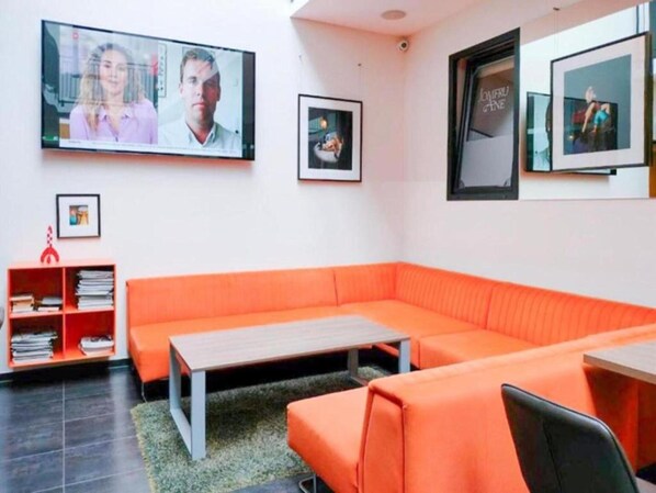 Una habitación moderna con un sofá naranja, una mesita y una estantería.