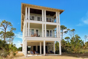 Un bâtiment à deux étages doté de balcons, d’un patio couvert et entouré de végétation.