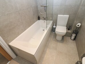 Une salle de bain moderne équipée d’une baignoire, de toilettes et d’une douche.