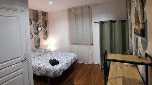 A bedroom with a bed, a bedside table, a chair, and a window with curtains. - La Halte Vésulienne (Vesoul)