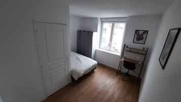 A room with a bed, a desk, a window, and a door.