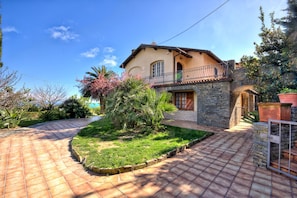 A house with a stone facade, a balcony, and a paved driveway. - Apartment in a villa with a private garden, 600 meters from the beaches (San Lorenzo al Mare)