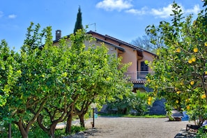 A house with a balcony, surrounded by trees and a gravel driveway. - Apartment in a villa with a private garden, 600 meters from the beaches (San Lorenzo al Mare)