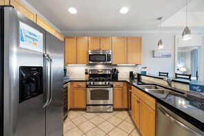 Una cocina moderna con electrodomésticos de acero inoxidable, gabinetes de madera y piso de baldosas.
