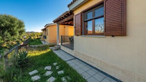 A residential building with a tiled patio, a covered outdoor seating area, and a garden with stepping stones. - Delightful and Spacious Villa in Capo Comino (Siniscola)
